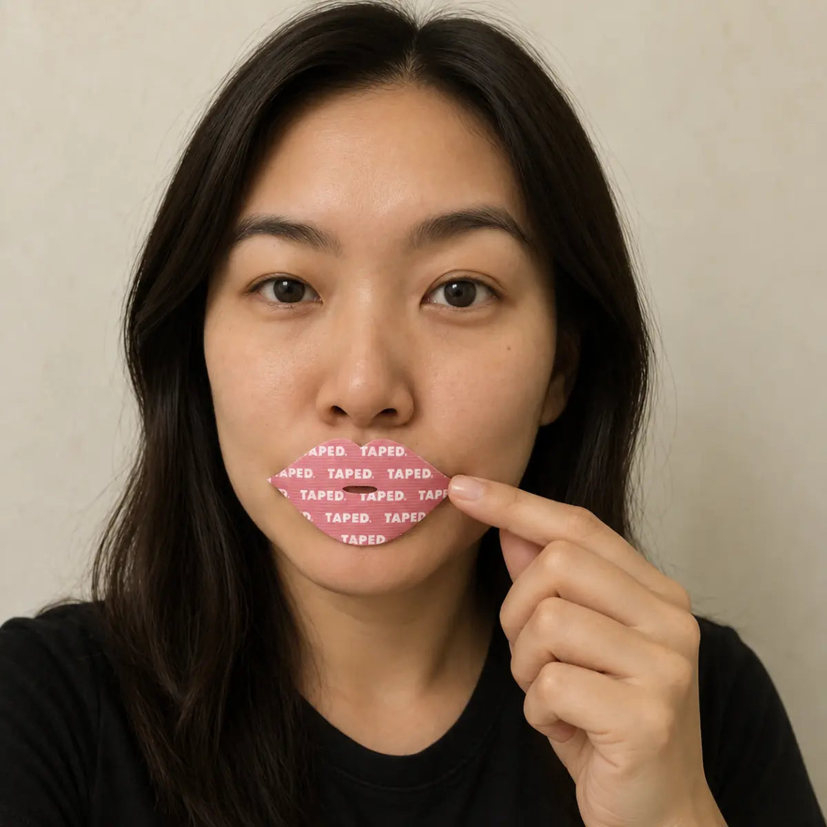 Woman gently pressing a pink lip-shaped TAPED strip onto closed lips